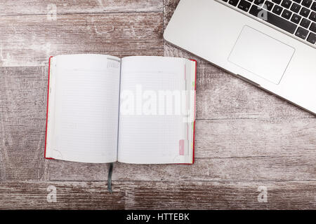 Laptop and a notebook for writing from above view on a wooden background Stock Photo