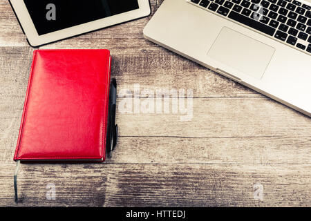 Laptop and a notebook for writing from above view on a wooden background Stock Photo