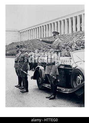 NUREMBERG RALLY 1930’s Chancellor Adolf Hitler in uniform wearing a swastika armband, standing in his Mercedes car, saluting members of  Workers Corps as they march by during a review at Nuremberg Zeppelin Field, part of ceremonies of the annual Nazi Party Congress. Stock Photo