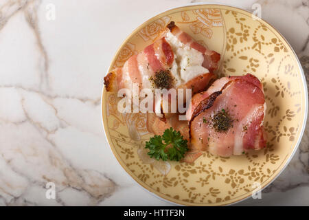 Close up of baked goat cheese wrapped in smoked bacon on plate Stock Photo