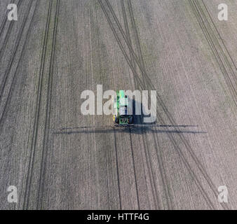 Tractor with hinged system of spraying pesticides. Fertilizing with a tractor, in the form of an aerosol, on the field of winter wheat Stock Photo