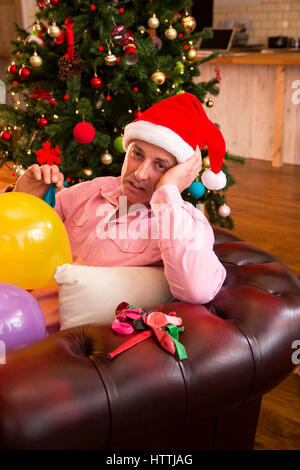 Mature man fed up with blowing up balloons at Christmas. Stock Photo