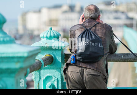 Man standing over railings while speaking on his phone. Stock Photo
