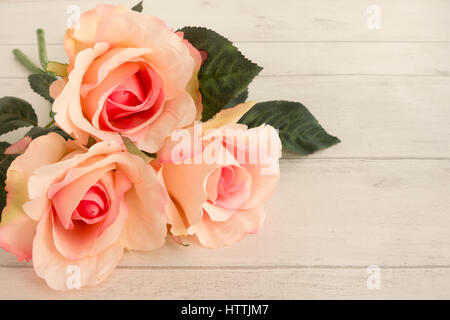 Closeup of three beautiful pink roses on light gray wooden background with lots of copy space. Stock Photo
