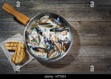 Oysters on crushed ice with antique oyster knife and silver fork with lemon fruit and pearls on a tin plate on a marble slab. Oysters on white plate w Stock Photo