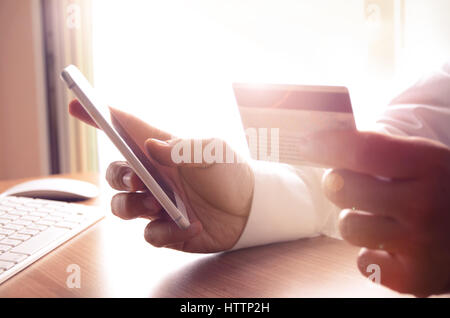 Closeup of man’s hands holding credit cards and using mobile phone. Concept for m-commerce, online shopping, m-banking, internet security. Stock Photo