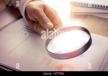 Business analytics and statistics. Businessman study report using a magnifying glass. Stock Photo
