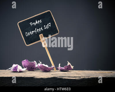 Happy Easter German words on a blackboard, concept image with colorful egg shells on a rustic wooden table Stock Photo