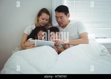 Family using digital tablet in bedroom Stock Photo