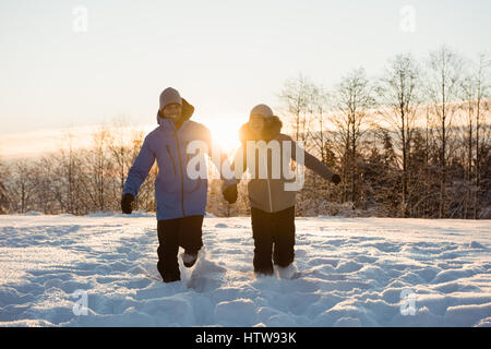 Couple walking on snow covered landscape Stock Photo