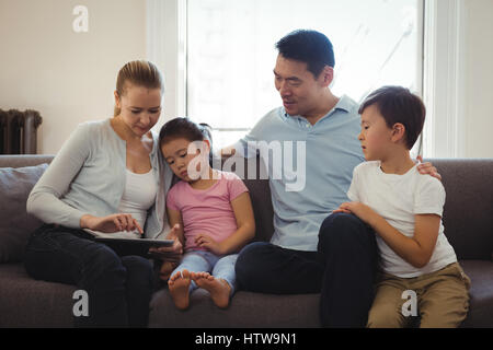 Parents and kids using digital tablet in living room Stock Photo