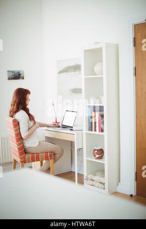 Pregnant woman using laptop in study room Stock Photo
