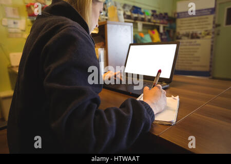 Woman using laptop and writing on notepad Stock Photo