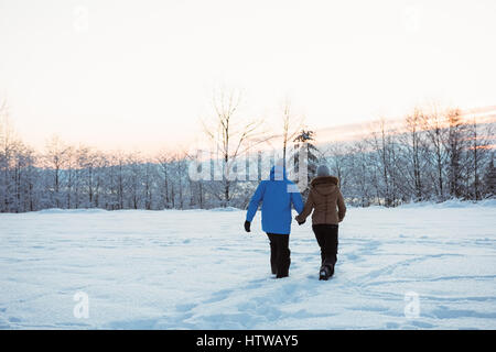 Couple walking on snow covered mountain Stock Photo