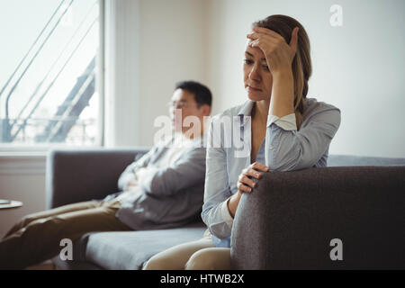 Couple sitting on sofa and ignoring each other Stock Photo