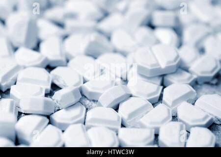 Macro of white tablets cut into small pieces. Blue color toned. Stock Photo