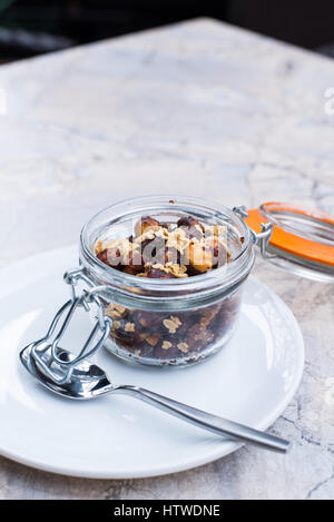 3/4 view of beer nuts in a clasp-top jar on a small white plate with a spoon Stock Photo