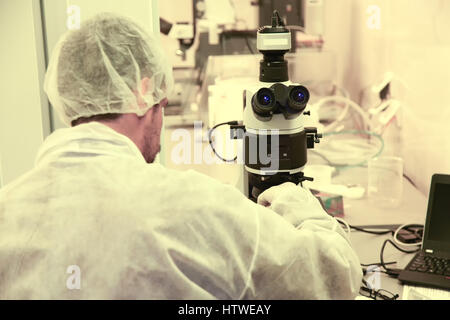 Laboratory technician using microscope in high tech laboratory Stock Photo