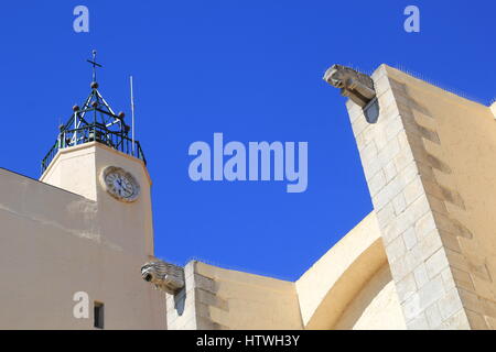 Gargoyles, bell tower and clock tower against blue sky on a church in the South of France Stock Photo