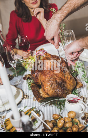Partial view of man carving roasted turkey at table served for Christmas Stock Photo