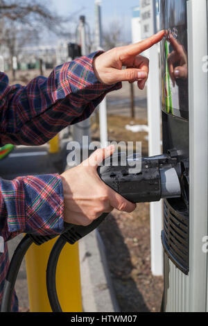 Woman inserting cable back into charging station Stock Photo
