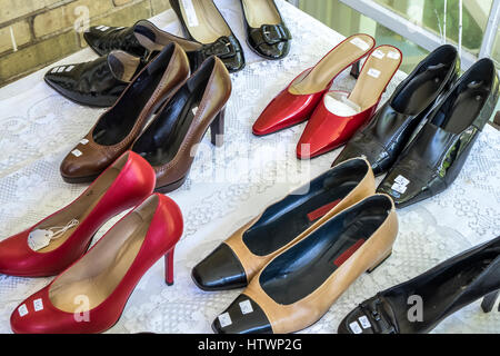 Pairs of women's shoes with price tags on a lace covered table. Stock Photo