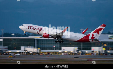 Air Canada Rouge plane airplane Boeing 767 (767-300ER) wide-body jet airliner take taking off at dusk twilight Vancouver International Airport Stock Photo