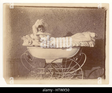 Original Victorian photograph of baby wearing ornate lace bonnet sitting in a pram, U.K. Stock Photo