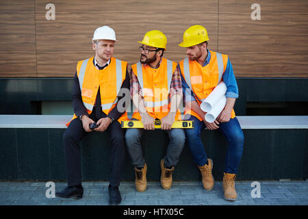Three inspectors in uniforms amd helmets discussing new project Stock Photo