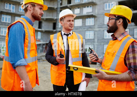 Young builders with walkie-talkies interacting at construction-site Stock Photo