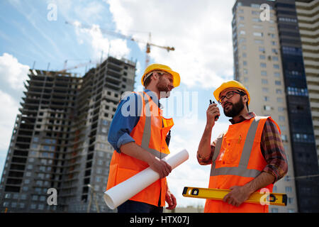 Contractor speaking on walkie-talkie with co-worker near by Stock Photo