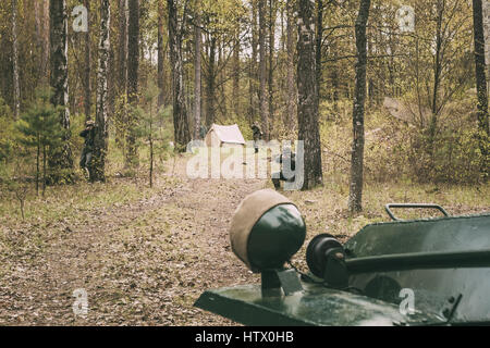 Unidentified Re-enactors Dressed As German Wehrmacht Infantry Soldiers In World War II Shooting From Rifles In Russian Armoured Soviet Scout Car Ba-64 Stock Photo