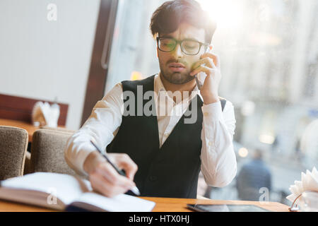 Young man organizing work and speaking to co-worker by the phone Stock Photo