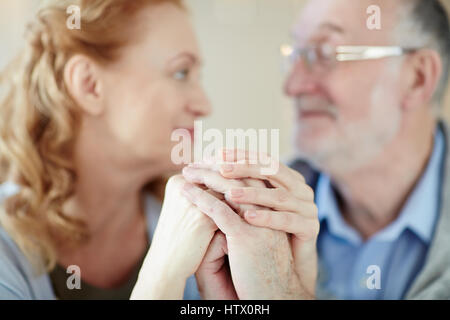Portrait of mature loving couple caring and supporting each other throughout the years, looking at each other and holding hands Stock Photo
