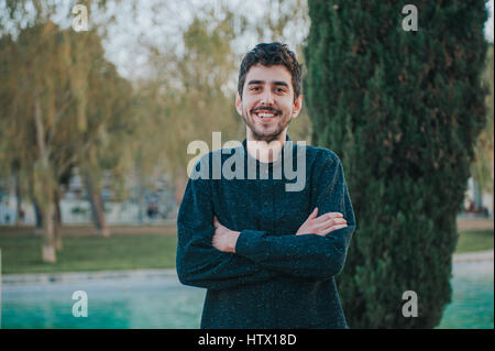 young mexican man with crossed arms in a park Stock Photo