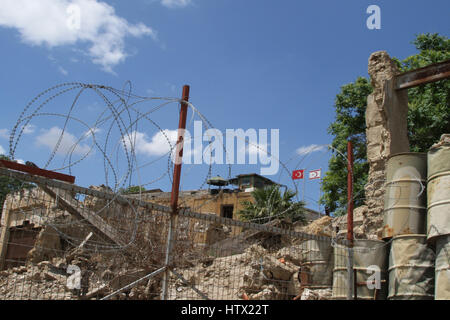 A sentry post with the flags of the Turkish Republic of Northern Cyprus and Turkey overlook rubble and razor wire on the green line in Nicosia, Cyprus Stock Photo