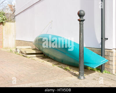 A boat secured against the wall of a house down at the waterfront of Wivenhoe. Stock Photo