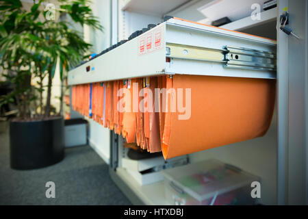 old and used orange paper File Folders in a metal filing cabinet.Cupboard with suspension files Stock Photo