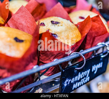 Vegan cranberry muffins on display in bakery in red paper liners Stock Photo