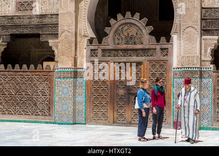 Fes, Morocco.  Medersa Bou Inania.  Tourists with Guide in the interior Courtyard. Stock Photo