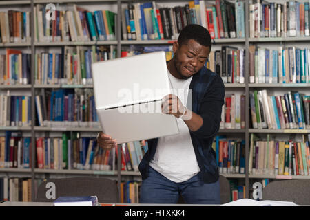African Male Student Throwing Laptop And Want To Destroy It - Shallow Depth Of Field Stock Photo