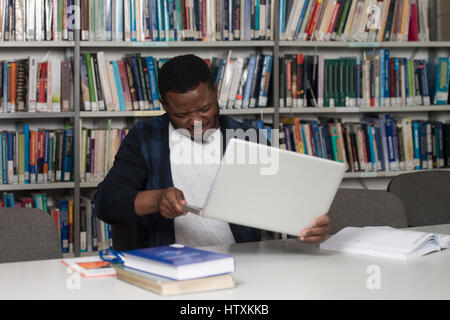 African Male Student Throwing Laptop And Want To Destroy It - Shallow Depth Of Field Stock Photo