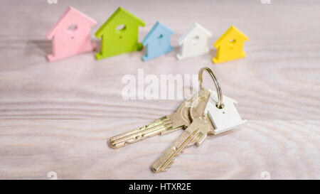 Silver Keychain laying on wooden Surface in front of miniature symbol of various coloured houses staying in line Stock Photo
