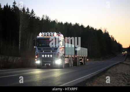 SALO, FINLAND - DECEMBER 6, 2016: Customized Scania truck of MHL-Trans with beautiful lighting accessoriesmoves along rural road after sunset. Stock Photo