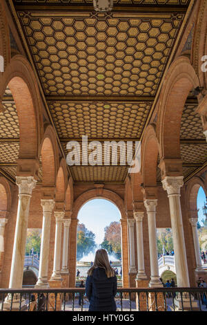 Woman standing inside the porch of Seville Plaza de Espana, Spain. She observes one of the picturesque landmark of the nation Stock Photo