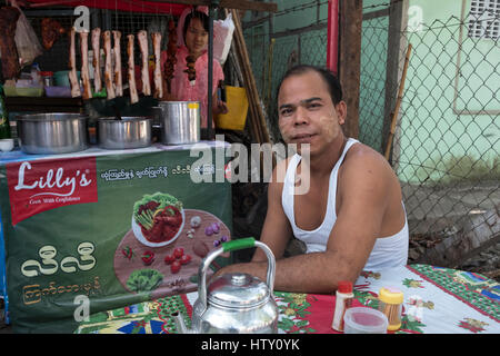 A young man relaxes at a Pansodan Street food stall in Yangon, Yangon Region, Myanmar. Stock Photo