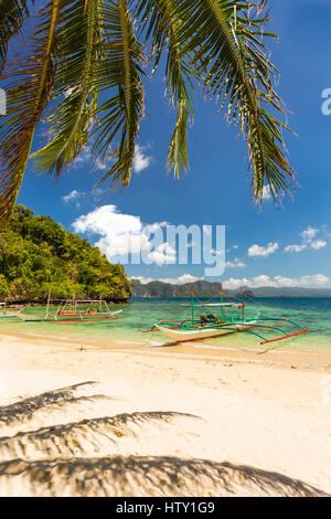 Traditional banca boats in clear water at the beach near Cudugnon Cave, El Nido, Palawan Island, Philippines Stock Photo