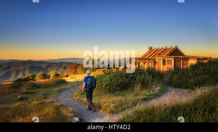 Young hiker with backpack approaching Craigs Hut, built as the the set for Man from Snowy River movie in the Victorian Alps, Australia Stock Photo