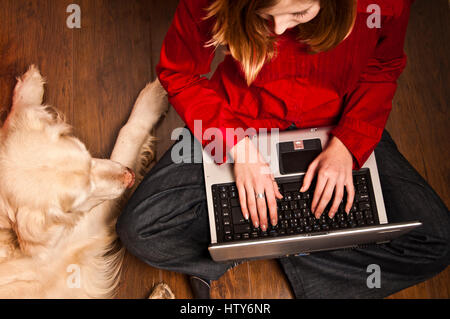 girl student working on laptop in company of her dog Stock Photo