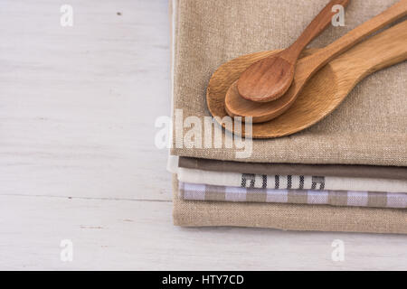 Stack of linen cotton kitchen towels, handmade wooden spoons, on white kitchen table, Provence style, interior design, coceptual Stock Photo